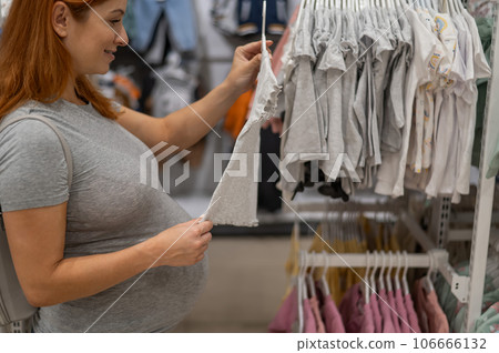 Caucasian pregnant woman chooses baby things in the store.  106666132