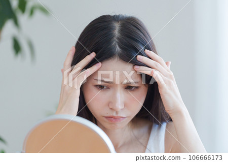 A woman checking her hairline 106666173