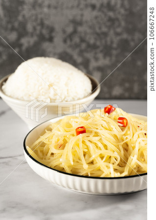 Stir-fried potato shreds and rice on a stone slab table. Stir-fried potato shreds and rice on a stone slab table. 106667248