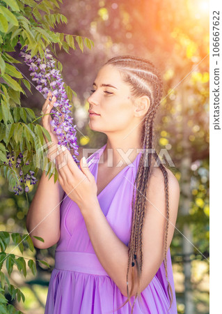 Woman wisteria lilac dress. Thoughtful happy mature woman in purple dress surrounded by chinese wisteria 106667622