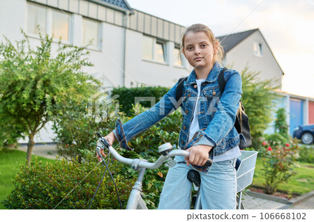 Schoolgirl child 10, 11 years old with backpack on bicycle on street near house Schoolgirl child 10, 11 years old with backpack on bicycle on street near house 106668102