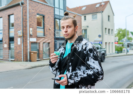 Young hipster male using smartphone, smoking disposable electronic cigarette 106668178