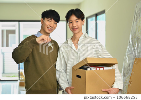 Happy asian gay couple holding cardboard box and sowing key of new home. LGBTQ, relocation and real estate property Happy asian gay couple holding cardboard box and sowing key of new home. LGBTQ, relocation and real estate property 106668255