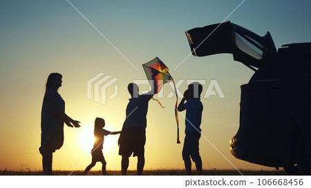 family traveling by car. family watching the sunset silhouette next to the car in the park. family playing kite ball. people in the park. family lifestyle car camping resting in nature family traveling by car. family watching the sunset silhouette next to the car in the park. family playing kite ball. people in the park. family lifestyle car camping resting in nature 106668456