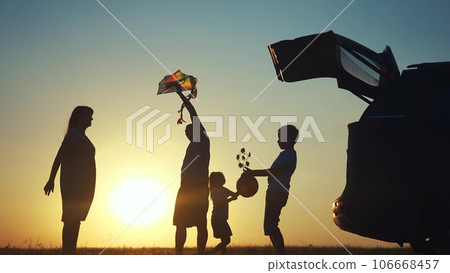 family traveling by car. family watching the sunset silhouette next to the car in the park. family playing kite ball. people in the park. family car lifestyle camping resting in nature family traveling by car. family watching the sunset silhouette next to the car in the park. family playing kite ball. people in the park. family car lifestyle camping resting in nature 106668457