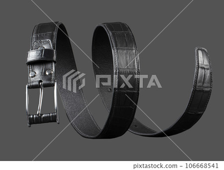 Black leather belt twisted in a spiral on a gray background. Black leather belt twisted in a spiral on a gray background. 106668541