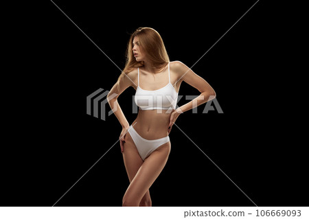 Portrait of young beautiful woman in white color lingerie isolated over black background. 106669093