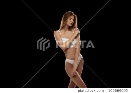 Portrait of young attractive woman in white color lingerie isolated over black background. Portrait of young attractive woman in white color lingerie isolated over black background. 106669095