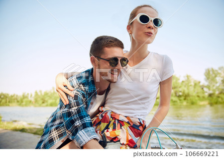 Portrait of young couple, laughing woman and her boyfriend going for a bike ride on a sunny summer day. Romantic vacations concept. 106669221