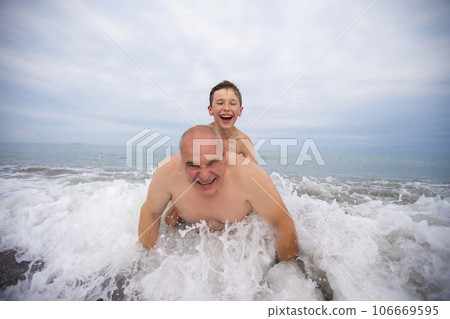 Happy boy swims and plays with grandpa on the beach. Happy boy swims and plays with grandpa on the beach. 106669595