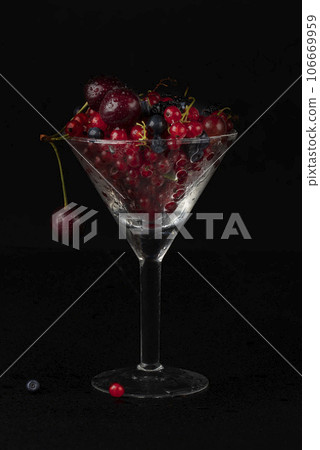 Summer berries in a glass glass on a dark background. 106669959