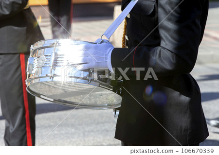 The silver drum in the hands of a military band musician sparkles in the sun. The silver drum in the hands of a military band musician sparkles in the sun. 106670339