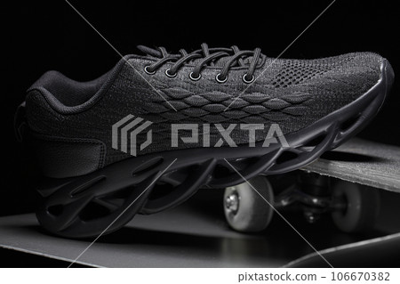 A black sneaker stands on a skateboard. Sport shoes. A black sneaker stands on a skateboard. Sport shoes. 106670382