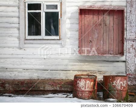 Background of an old and abandoned house. Wooden wall with peeling paint and rusty barrels. 106670409