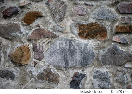An ancient stone wall consisting of stones of different shapes and composition. An ancient stone wall consisting of stones of different shapes and composition. 106670594
