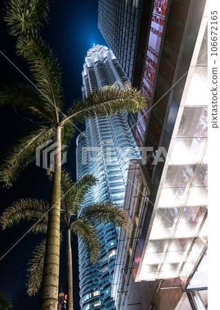 Petronas Twin Towers shining in the night sky beyond the palm trees Petronas Twin Towers shining in the night sky beyond the palm trees 106672165