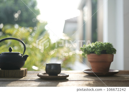 Tea cup and metal teapot and plant pot on wooden table outdoor relaxing drinking 106672242