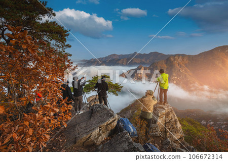 tourist with backpack admiring landscape in Autumn In the morning, a sea of mist flows through the river in the valley In the autumn at Jebibong of Waraksan Mountain National Park, South Korea. tourist with backpack admiring landscape in Autumn In the morning, a sea of mist flows through the river in the valley In the autumn at Jebibong of Waraksan Mountain National Park, South Korea. 106672314