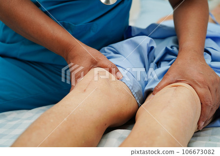 Doctor checking Asian elderly woman patient with scar knee replacement surgery in hospital. 106673082