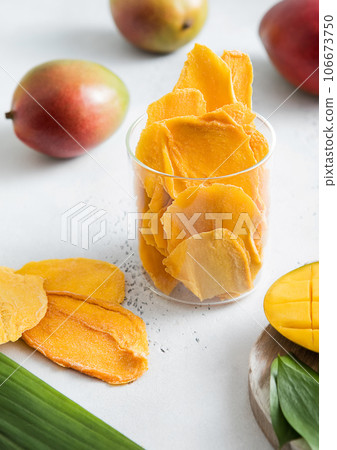 Dried mango pieces in glass jar and raw fruit on light background with raw fruits. 106673750