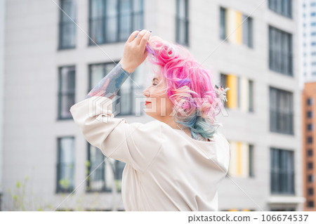 Portrait of a middle-aged woman with multi-colored hair walks on the streets of the city. 106674537