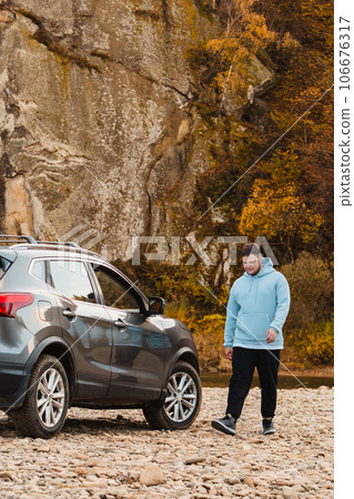 man at the rocky beach in mountain river near car man at the rocky beach in mountain river near car 106676317