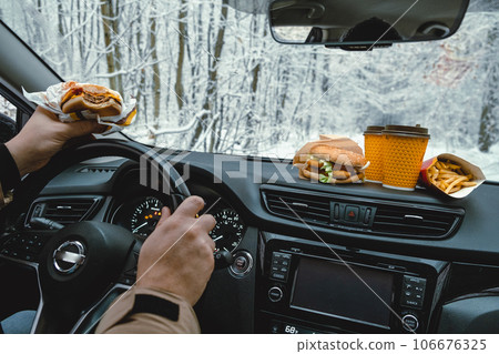 man driving stopped to eat fast food car behind windshield winter landscape 106676325