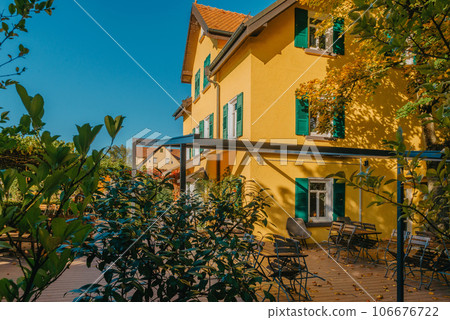 Image of a empty coffee tables arranged in backyard of a house. Autumn in Germany, Europe. Outdoor table in street cafe. autumn outdoor cafe wooden furniture old europe. Autumn photo of old-fashioned 106676722