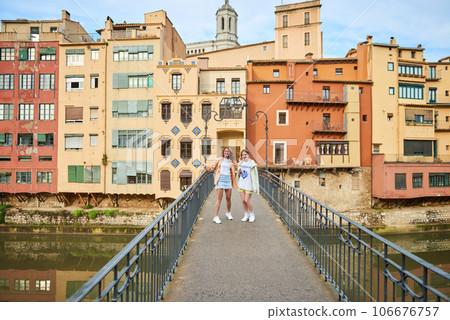 2 girls on the bridge. View of old town Girona, Catalonia, Spain, Europe. Summer travel. 106676757