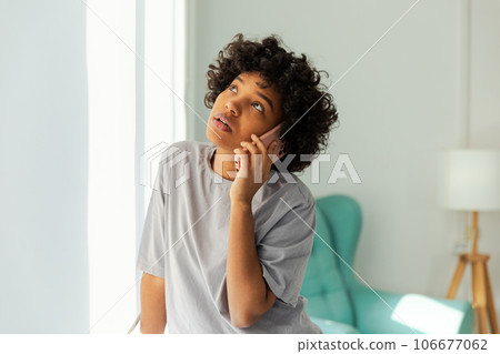 African american girl talking on smartphone at home indoor. Young woman with cell phone chatting with friends. Smiling teen girl making answering call by cellphone. Lady having conversation by mobile African american girl talking on smartphone at home indoor. Young woman with cell phone chatting with friends. Smiling teen girl making answering call by cellphone. Lady having conversation by mobile 106677062