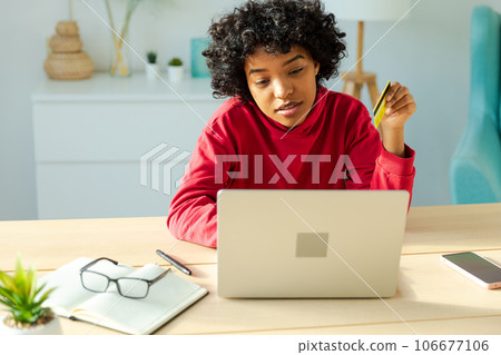 African american woman using laptop shopping online paying with gold credit card. Girl sitting at home buying on Internet enter credit card details. Online shopping ecommerce delivery service 106677106