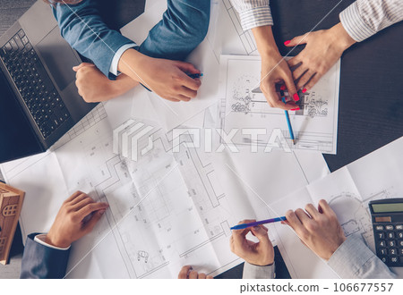 Managers sitting in the office and discussing the drawings of the house. 106677557