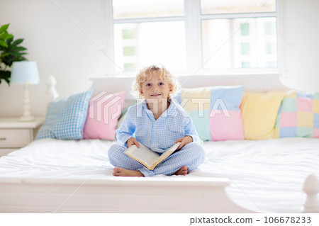 Child reading book in bed. Kids read in bedroom. 106678233