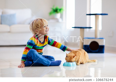 Child playing with cat at home. Kids and pets. 106678244