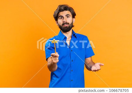 Magician witch young man gesturing with magic wand making wish come true, casting magician spell 106678705