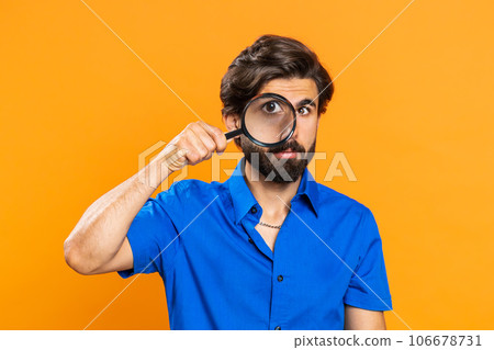 Investigator researcher man with magnifying glass near face, looking into camera with big zoom eye 106678731