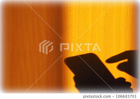 A scene where the shadow of someone operating a smartphone is reflected on a wooden wall (illustration style) A scene where the shadow of someone operating a smartphone is reflected on a wooden wall (illustration style) 106683701