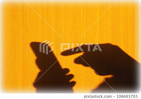 A scene where the shadow of the person operating the smartphone is reflected on the wood-grained wall A scene where the shadow of the person operating the smartphone is reflected on the wood-grained wall 106683703