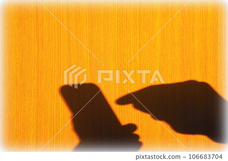 A scene where the shadow of the person operating the smartphone is reflected on the wood-grained wall A scene where the shadow of the person operating the smartphone is reflected on the wood-grained wall 106683704