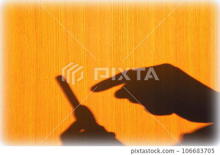 A scene where the shadow of the person operating the smartphone is reflected on the wood-grained wall 106683705