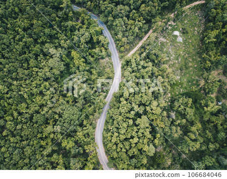 Aerial view of the road cut throug the green forest on the highland mountains in Chiang Rai province, Thailand. Beautiful view of the road from drone. Aerial view of the road cut throug the green forest on the highland mountains in Chiang Rai province, Thailand. Beautiful view of the road from drone. 106684046