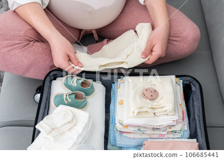 Anticipating the birth journey, pregnant woman meticulously packing, selecting essentials for her maternity hospital stay Anticipating the birth journey, pregnant woman meticulously packing, selecting essentials for her maternity hospital stay 106685441