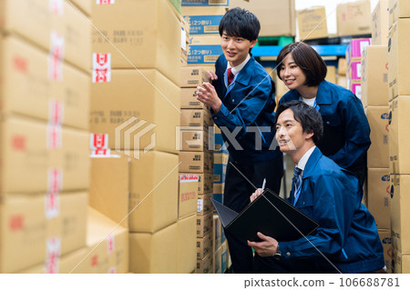 Young male and female businessmen wearing work clothes inspecting products in a warehouse at a distribution center Young male and female businessmen wearing work clothes inspecting products in a warehouse at a distribution center 106688781