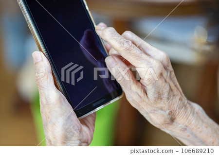 一位正在智能手機上努力工作的老婦人的手 一位正在智能手機上努力工作的老婦人的手 106689210