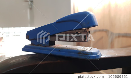 closeup view of an old rustic plastic stapler isolated on brown wooden background 106689561
