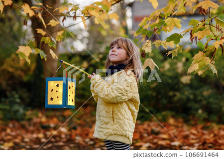 Little preschool kid girl holding selfmade traditional lanterns with candle for St. Martin procession. child happy about children and family parade in kindergarten. German tradition Martinsumzug 106691464