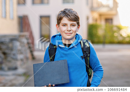 Happy little kid boy with satchel, walking. Schoolkid on the way to middle or high school. Excited child outdoors on school yard. Back to school. Kid holding chalk desk with copyspace for text Happy little kid boy with satchel, walking. Schoolkid on the way to middle or high school. Excited child outdoors on school yard. Back to school. Kid holding chalk desk with copyspace for text 106691484