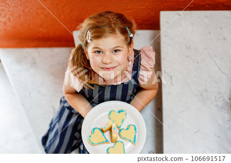 Happy little preschool girl celebrating birthday. Closeup of child with homemade biscuite cake, indoor. Happy healthy kid indoors Happy little preschool girl celebrating birthday. Closeup of child with homemade biscuite cake, indoor. Happy healthy kid indoors 106691517