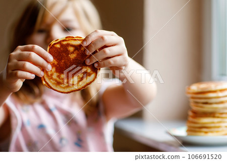 Little happy preschool girl with a large stack of pancakes for breakfast. Positive child eating healthy homemade food in the morning. Little happy preschool girl with a large stack of pancakes for breakfast. Positive child eating healthy homemade food in the morning. 106691520