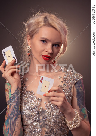 Blonde woman with a beautiful hairstyle and perfect make-up is posing with playing cards in her hands. Casino, poker. Blonde woman with a beautiful hairstyle and perfect make-up is posing with playing cards in her hands. Casino, poker. 106692083